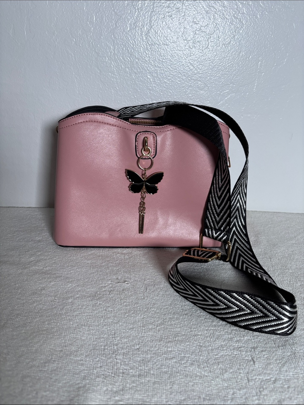Pink Crossbody Bag with Black Butterfly Charm and Patterned Strap
